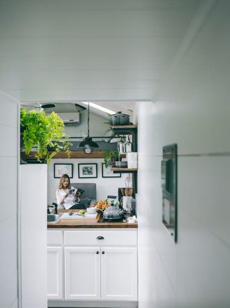Fau liest Buch in der Küche, links auf dem Schrank sind Indoor-Pflanzen zu sehen